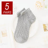 A pair of gray breathable mesh lace tube socks displayed on a white plate.