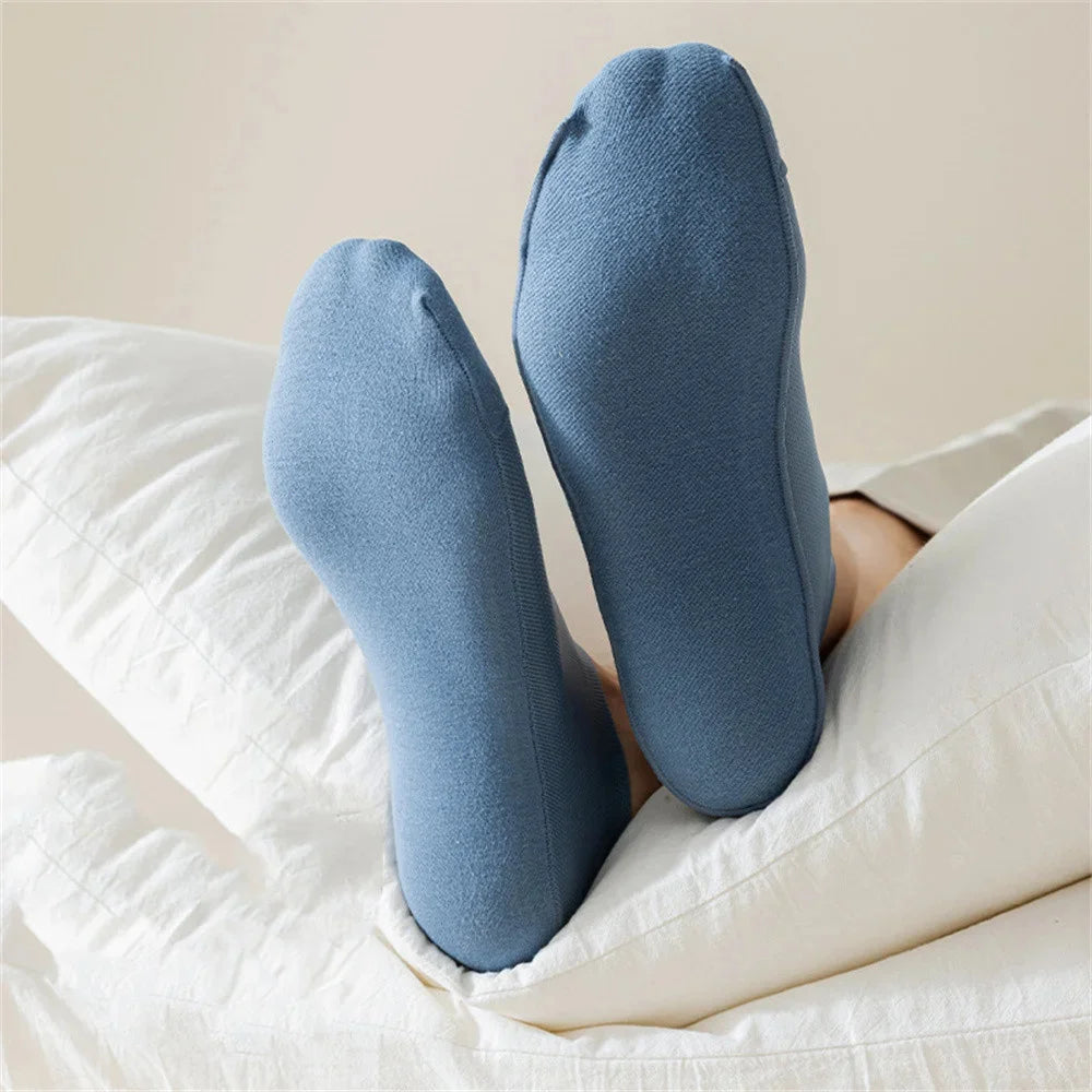 Une paire de chaussettes en maille bleues antidérapantes posées sur un linge blanc.