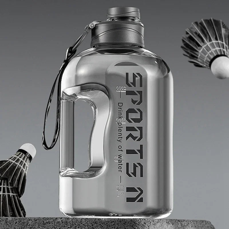 Klare, große wiederverwendbare Sportflasche mit Metallverschluss und Leine, auf grauer Oberfläche.