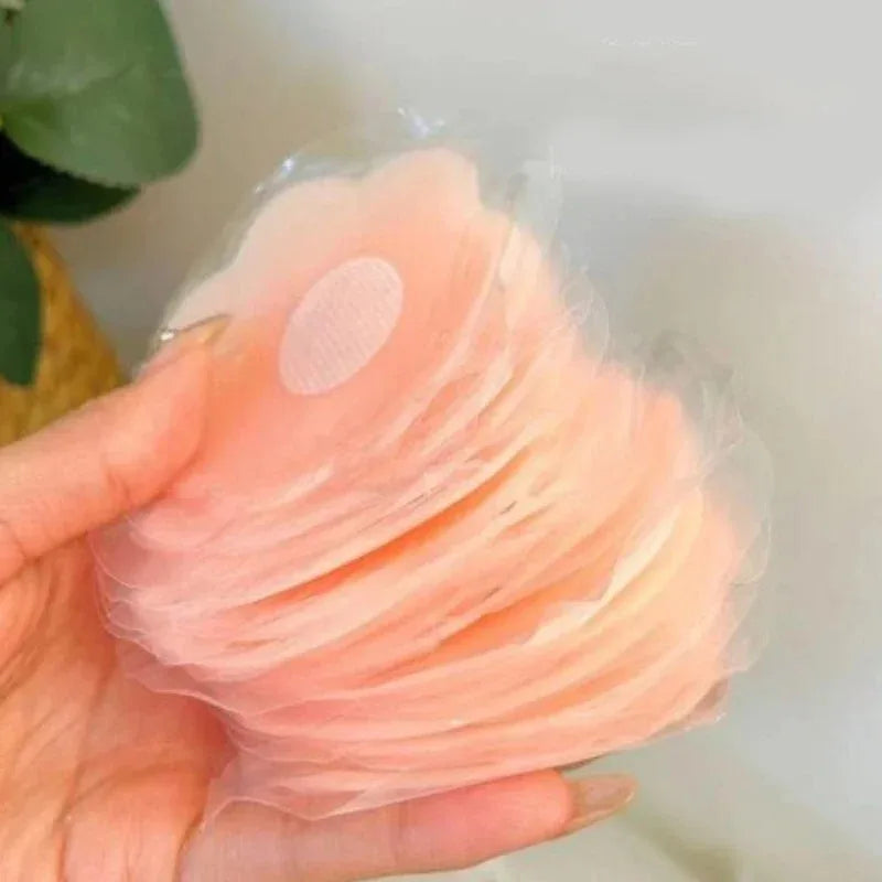 Une main tient un ensemble de cache-lèvres en silicone réutilisables de couleur pêche clair.