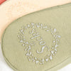 A close-up of a light green silicone anti-slip summer sock with embroidered initials.