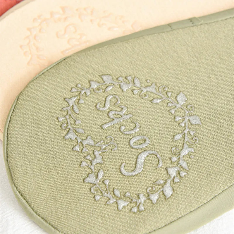 A close-up of a light green silicone anti-slip summer sock with embroidered initials.