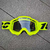Une paire de lunettes de protection jaune vif avec une lentille claire posée sur une surface grise.