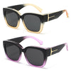 Black sunglasses with gold accents and purple lenses shown in a studio shot.