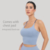 A woman models a light blue summer strappy yoga sports bra with an integrated fixed cup and chest pad.