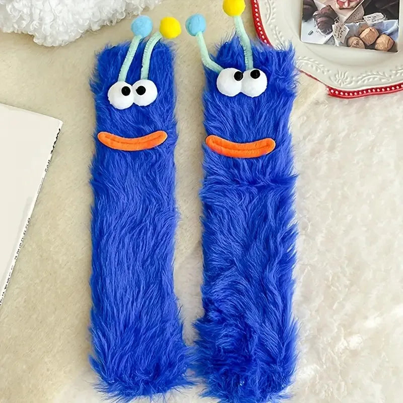 Pair of bright blue cartoon expression knit socks with yellow pom-poms