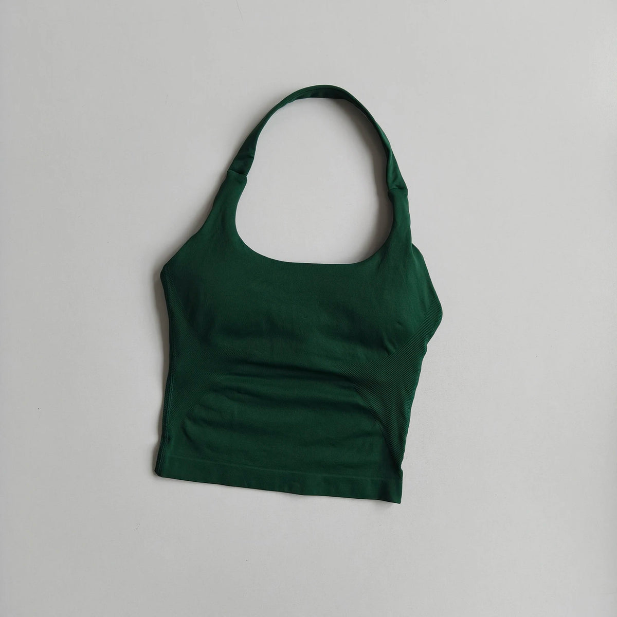 A dark green seamless yoga and pilates sports bra displayed against a white background.