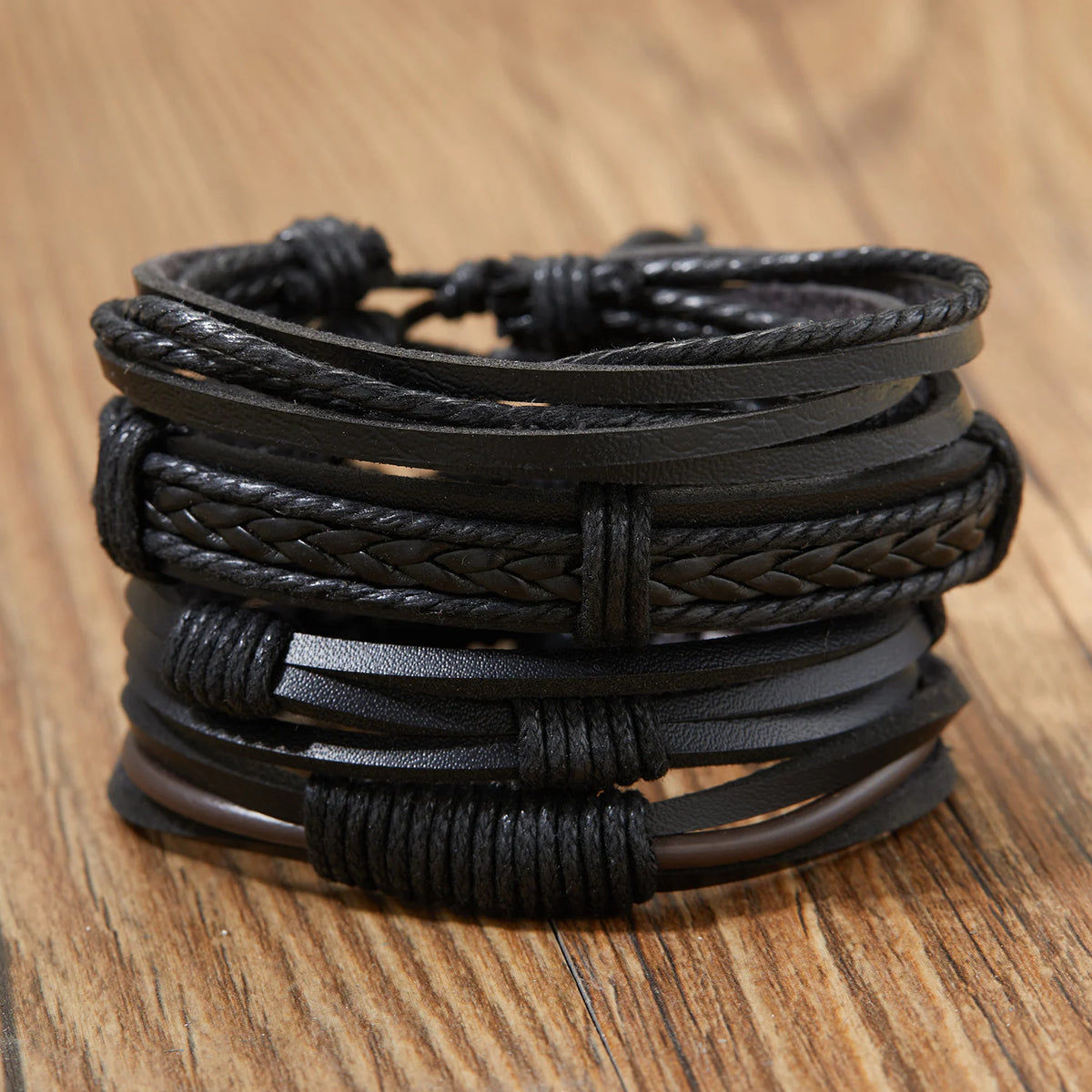 Stapel schwarzer Lederblatt-Feder-Armbänder auf einer Holzoberfläche