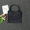 Black seamless yoga and pilates sports bra laid on a dark gray textured surface with pink tulips and a white card.
