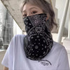 Primer plano de una mujer usando un pañuelo protector UV negro tipo paisley como mascarilla