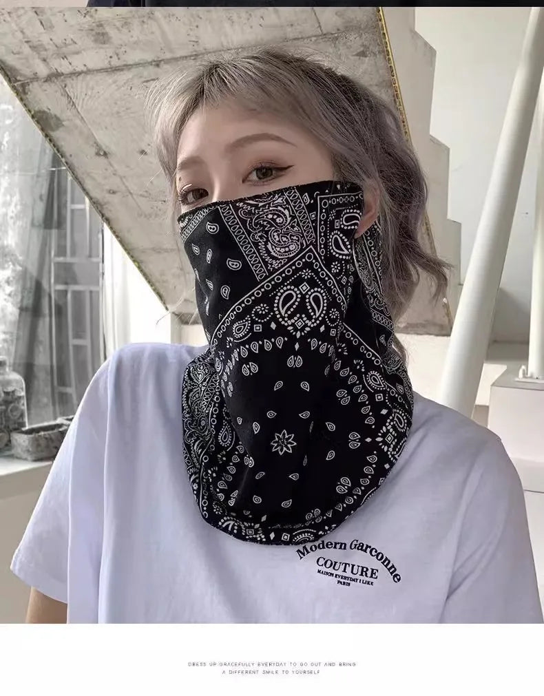 Primer plano de una mujer usando un pañuelo protector UV negro tipo paisley como mascarilla