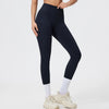 Person in dark navy seamless high-waist yoga leggings and white socks, standing in light athletic wear