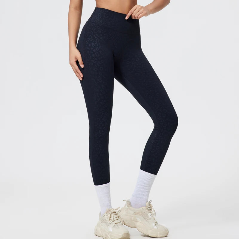 Person in dark navy seamless high-waist yoga leggings and white socks, standing in light athletic wear