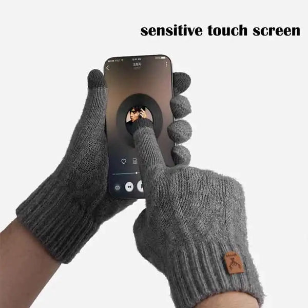 Gray knitted gloves holding a smartphone displaying a sensitive touch screen.