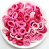 Haufen bunter rosa und roter Nylon-Elastik-Haargummis für Pferdeschwänze und Zöpfe.