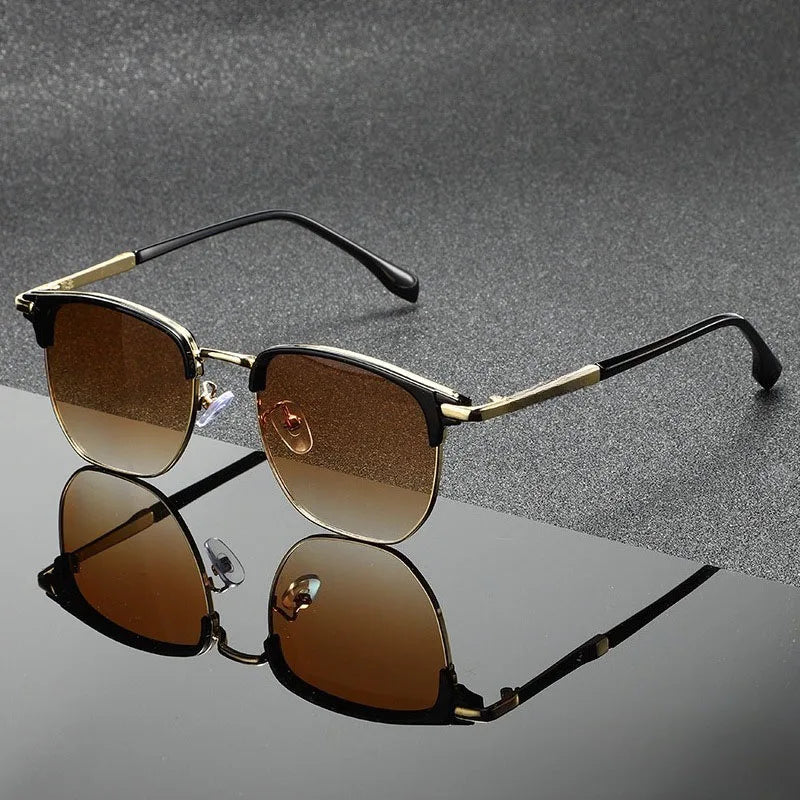 Vintage square sunglasses with gold metal frames and brown lenses resting on a reflective surface.