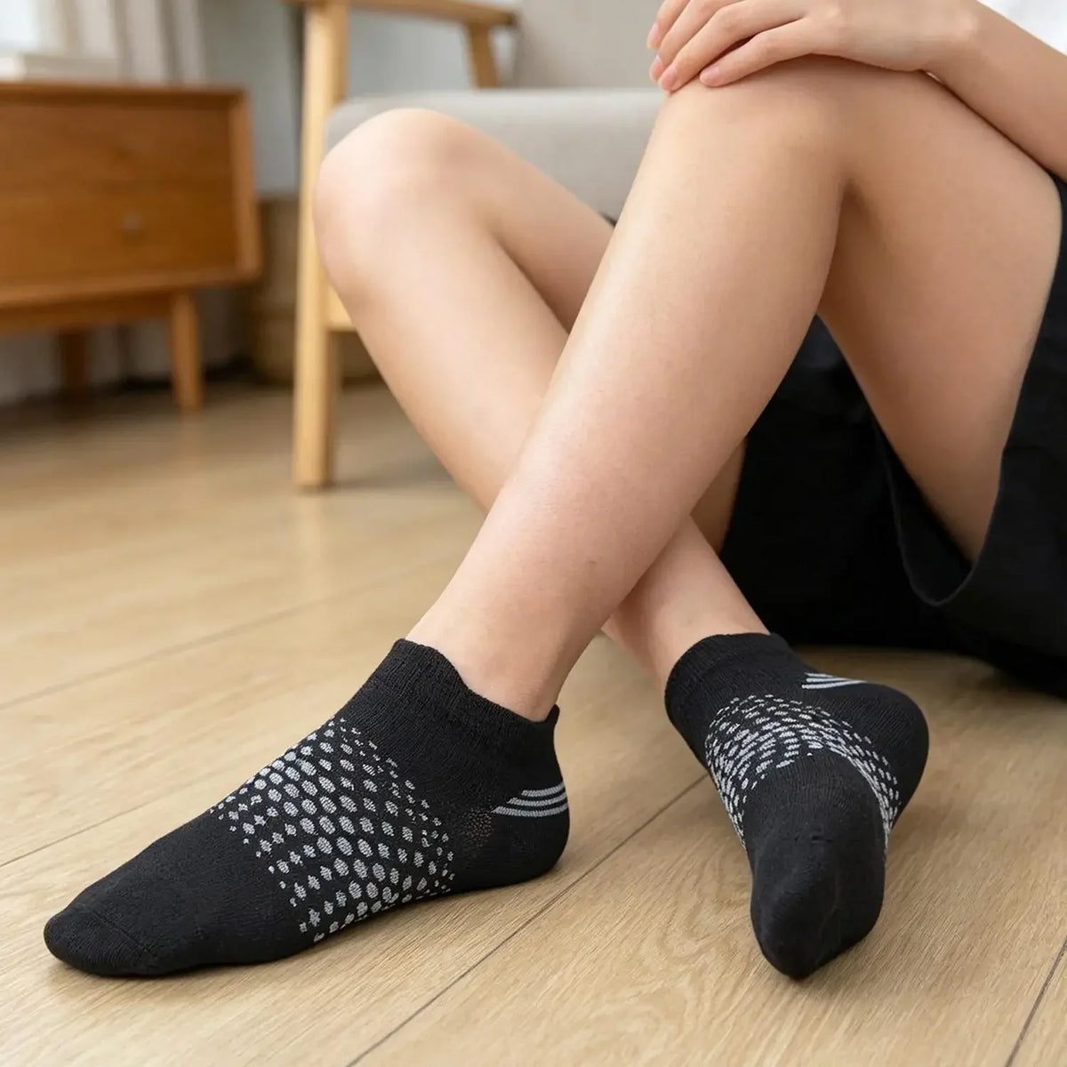 A pair of black breathable mesh ankle socks lying on a wooden floor.