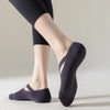 Una persona vistiendo calcetines de yoga y pilates ajustados de color gris oscuro, de pie contra un fondo claro.