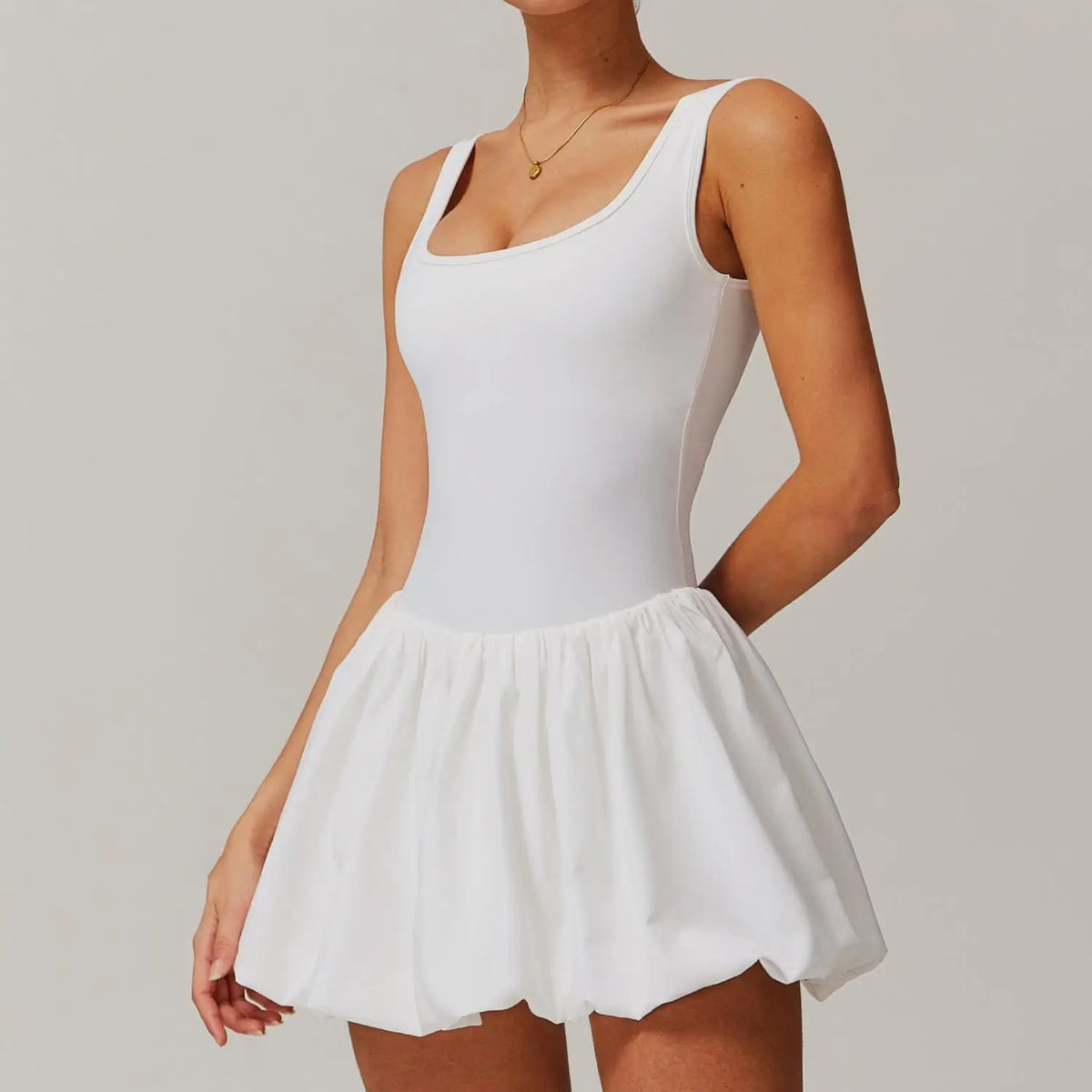 Eine Frau in einem weißen Sport-Tenniskleid mit figurbetontem Oberteil und plissiertem Rock.