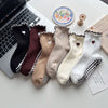 A collection of embroidered yoga socks in various neutral tones including black, brown, beige, and white.