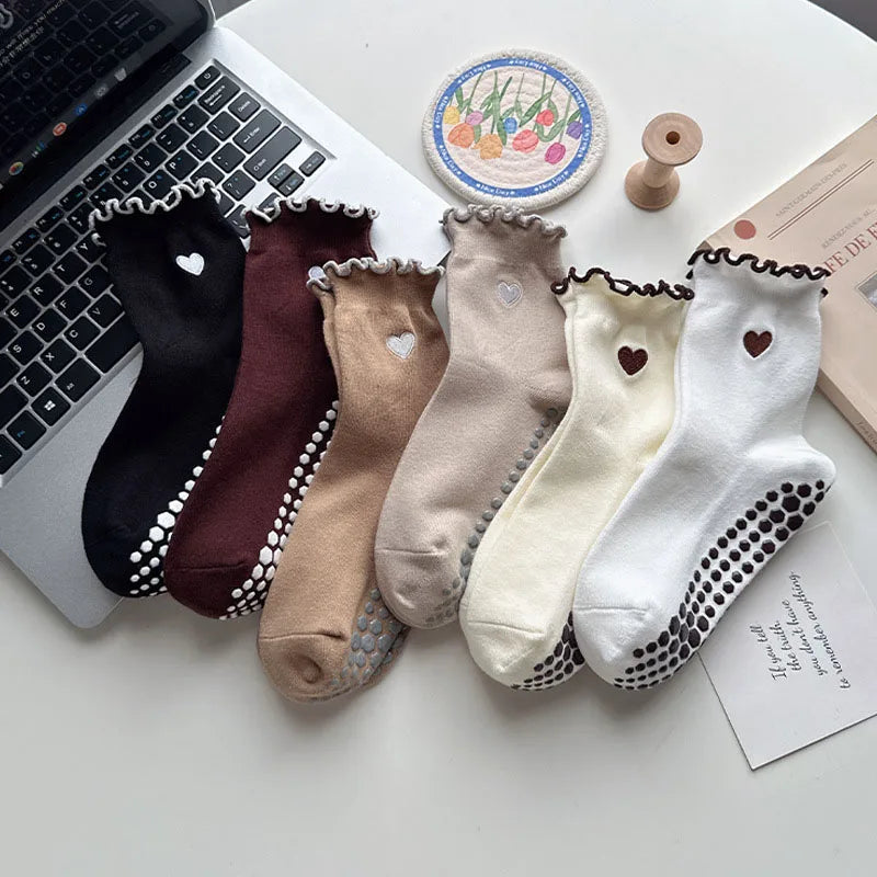 A collection of embroidered yoga socks in various neutral tones including black, brown, beige, and white.