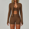 Model trägt ein nahtloses Sport-Yoga-Set in Braun mit langärmeligem Zip-Top und passenden Shorts.