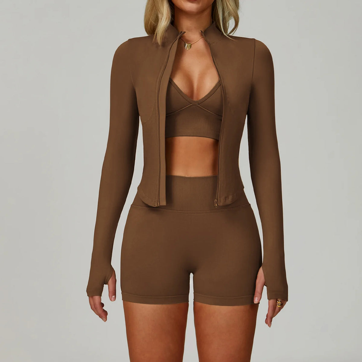 Model trägt ein nahtloses Sport-Yoga-Set in Braun mit langärmeligem Zip-Top und passenden Shorts.