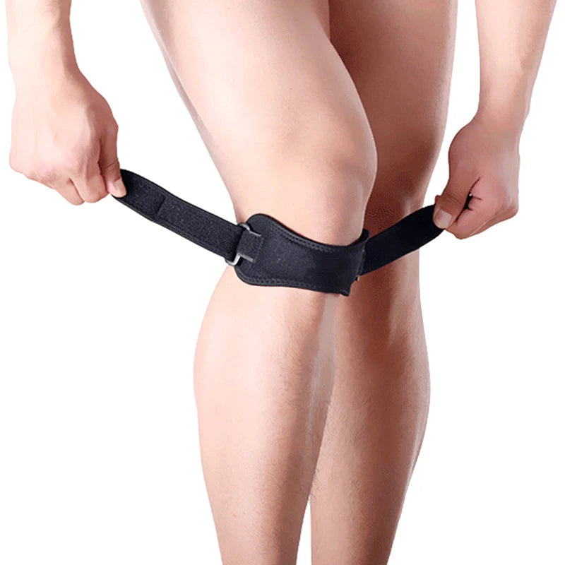A person is wearing a black adjustable patella tendon support brace on their knee.