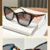 A pair of tortoiseshell-patterned square cat eye sunglasses displayed on a white book.