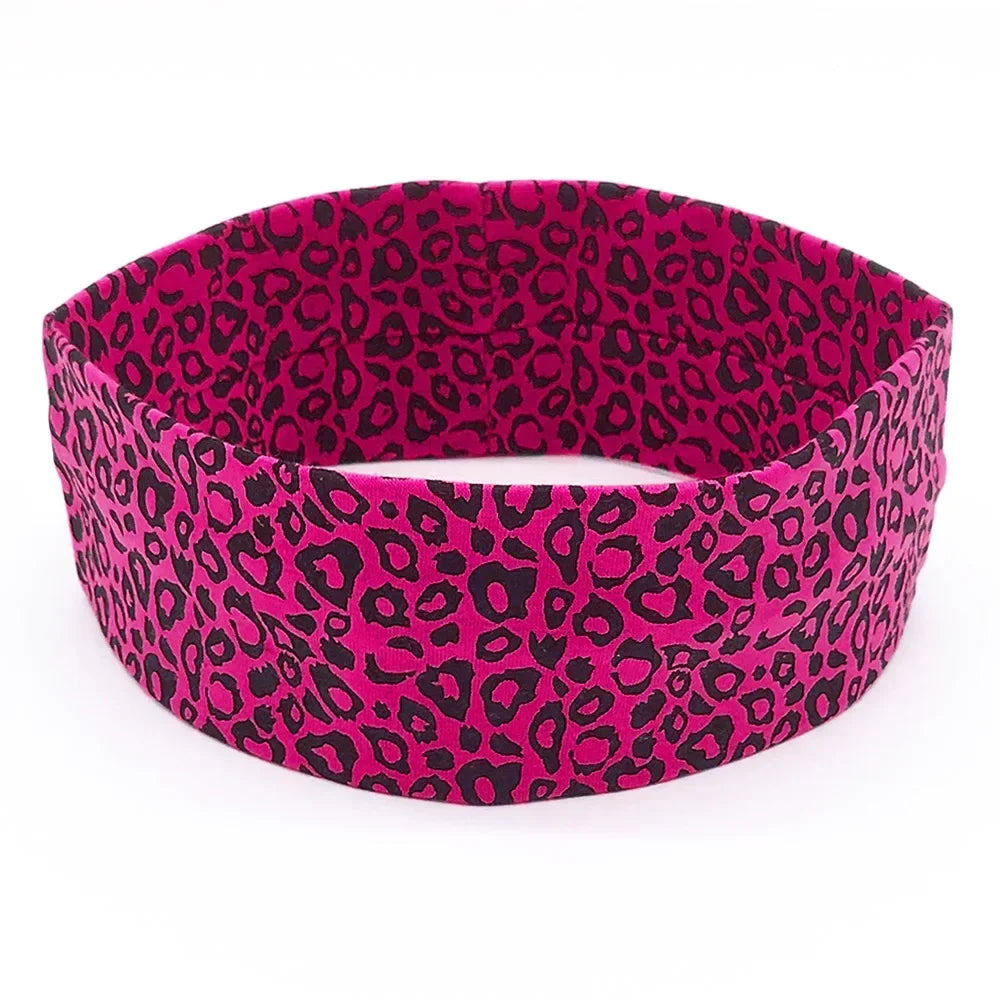 A women's sports headband featuring a vibrant pink and black leopard print pattern.