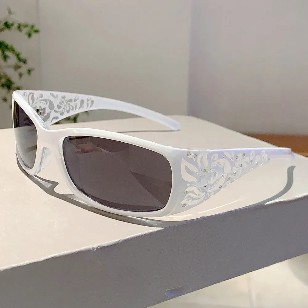 White frame sunglasses with silver rhinestone cat eye detailing resting on a white surface.