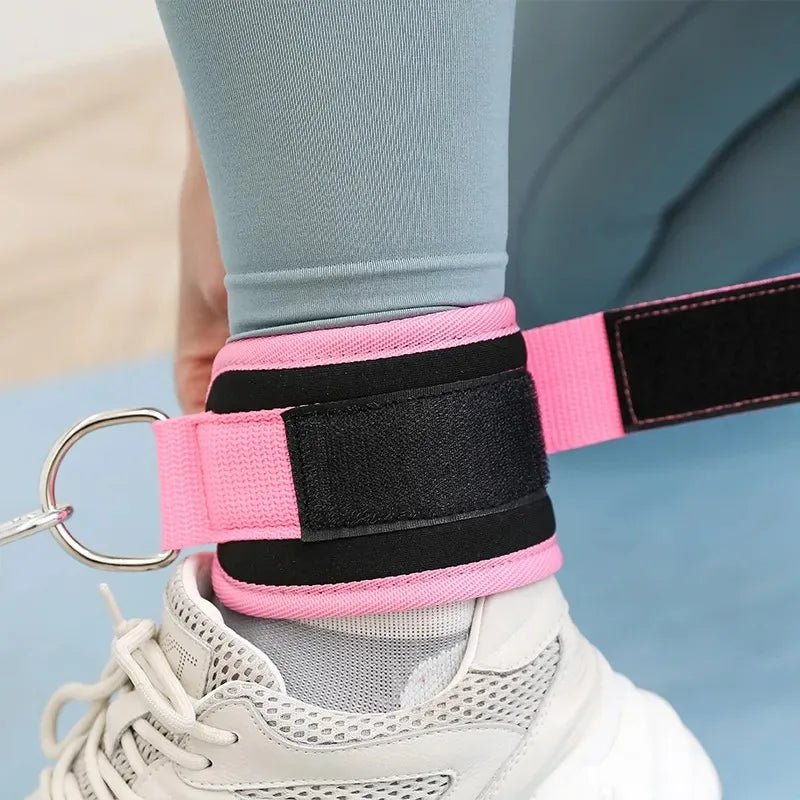 Pink and black neoprene ankle straps are being fitted onto a white athletic shoe for leg training.