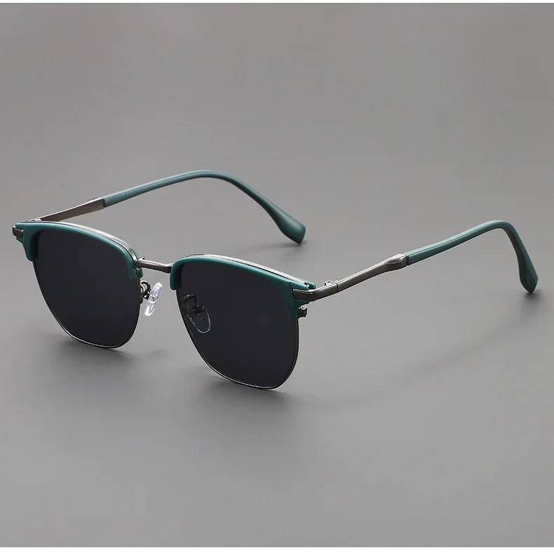 A pair of dark green classic square metal frame sunglasses resting on a gray surface.