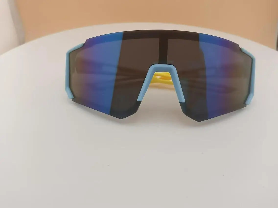 A pair of dark sunglasses with blue mirrored lenses and light blue frames resting on a white surface.