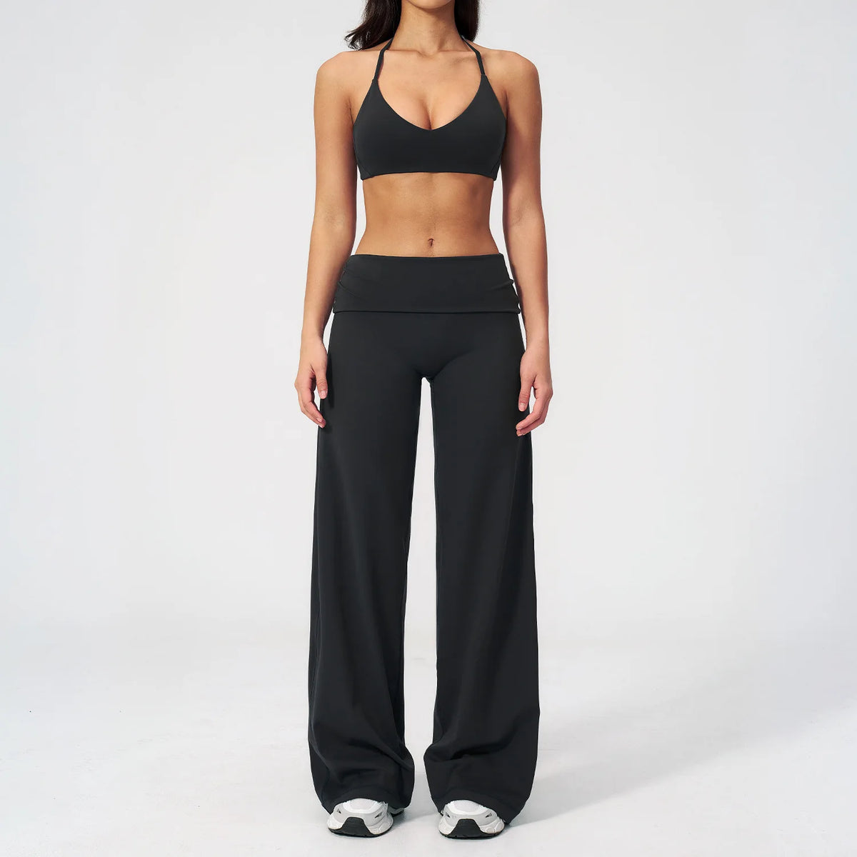 A woman wearing a black women's premium fitness tracksuit top and matching pants.