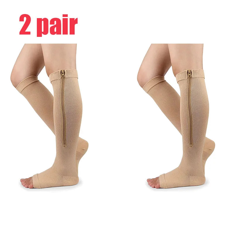 A pair of beige compression stockings with zippers shown on legs.