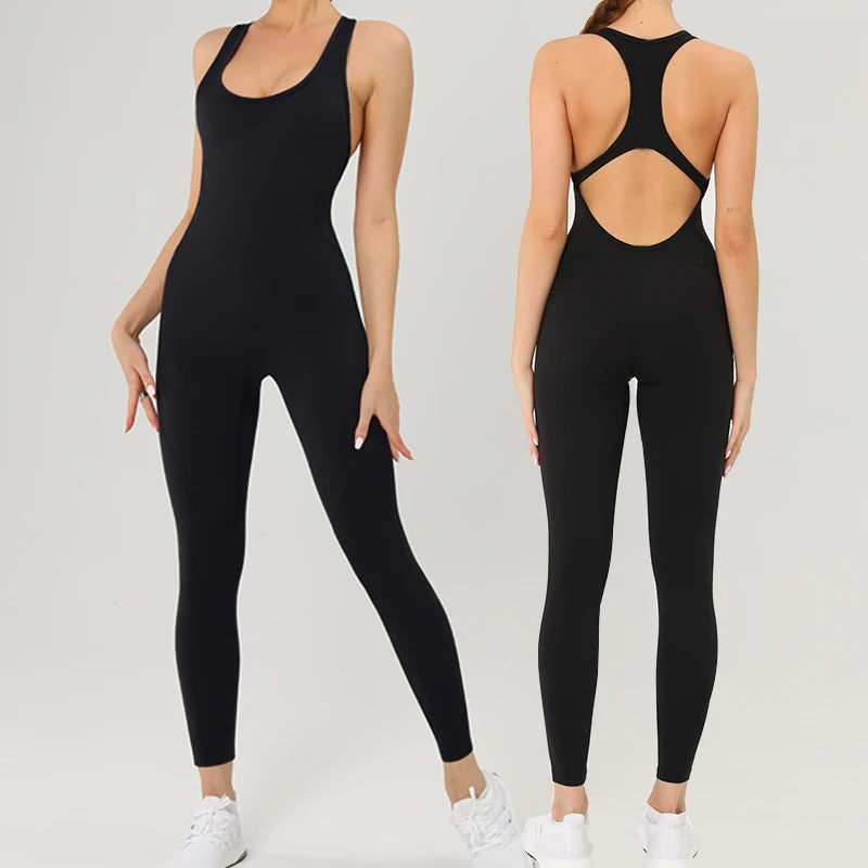 A woman models a black, form-fitting, backless fitness jumpsuit.