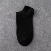 A black ankle sock lying flat on a gray textured surface.