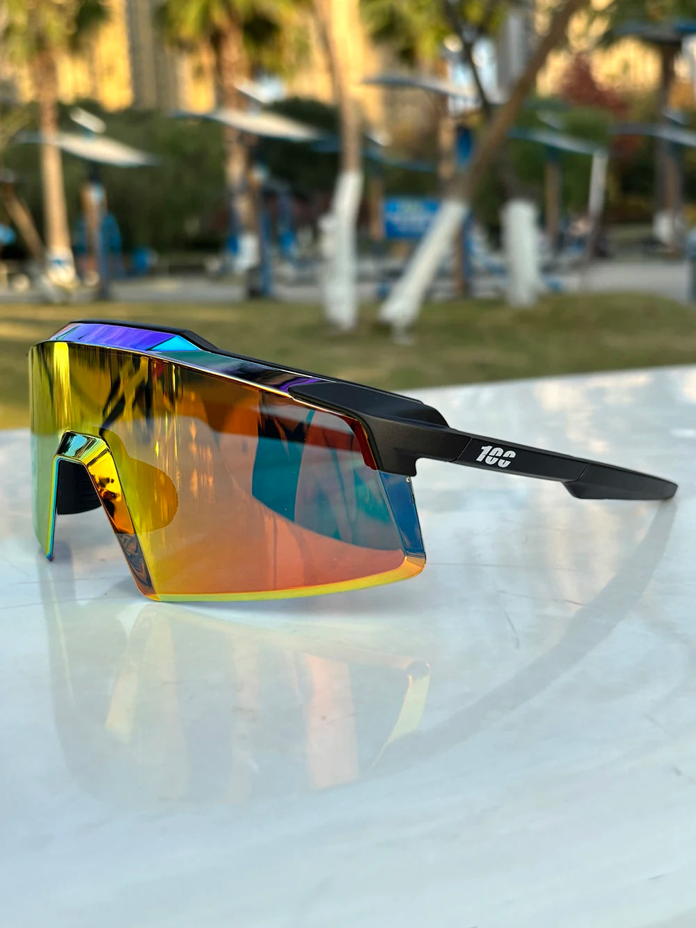 A pair of orange and purple tinted sports sunglasses resting on a white surface.