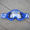 Lunettes de moto tout-terrain bleues avec des verres blancs et une sangle bleue posées sur une surface grise.