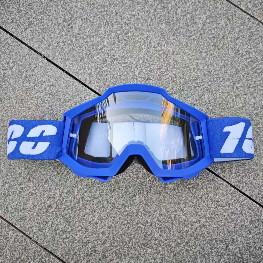 Lunettes de moto tout-terrain bleues avec des verres blancs et une sangle bleue posées sur une surface grise.