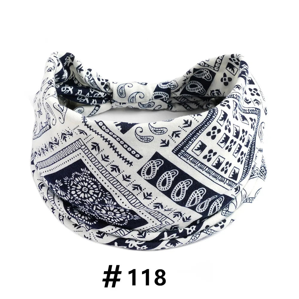 A close-up of a white and navy boho print cotton headband tied around a head.