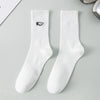 A pair of white men's athletic crew socks with a black embroidered logo on the calf.