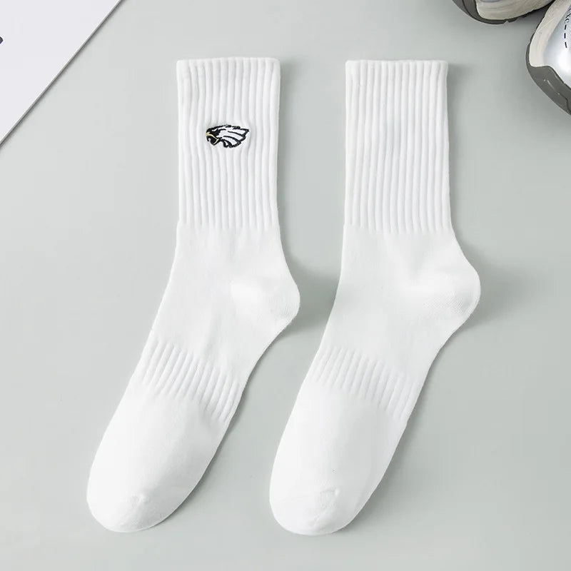 A pair of white men's athletic crew socks with a black embroidered logo on the calf.