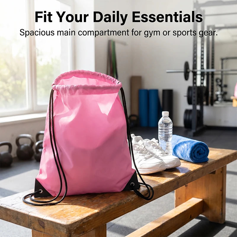 A pink nylon drawstring backpack is shown on a wooden table next to gym equipment.