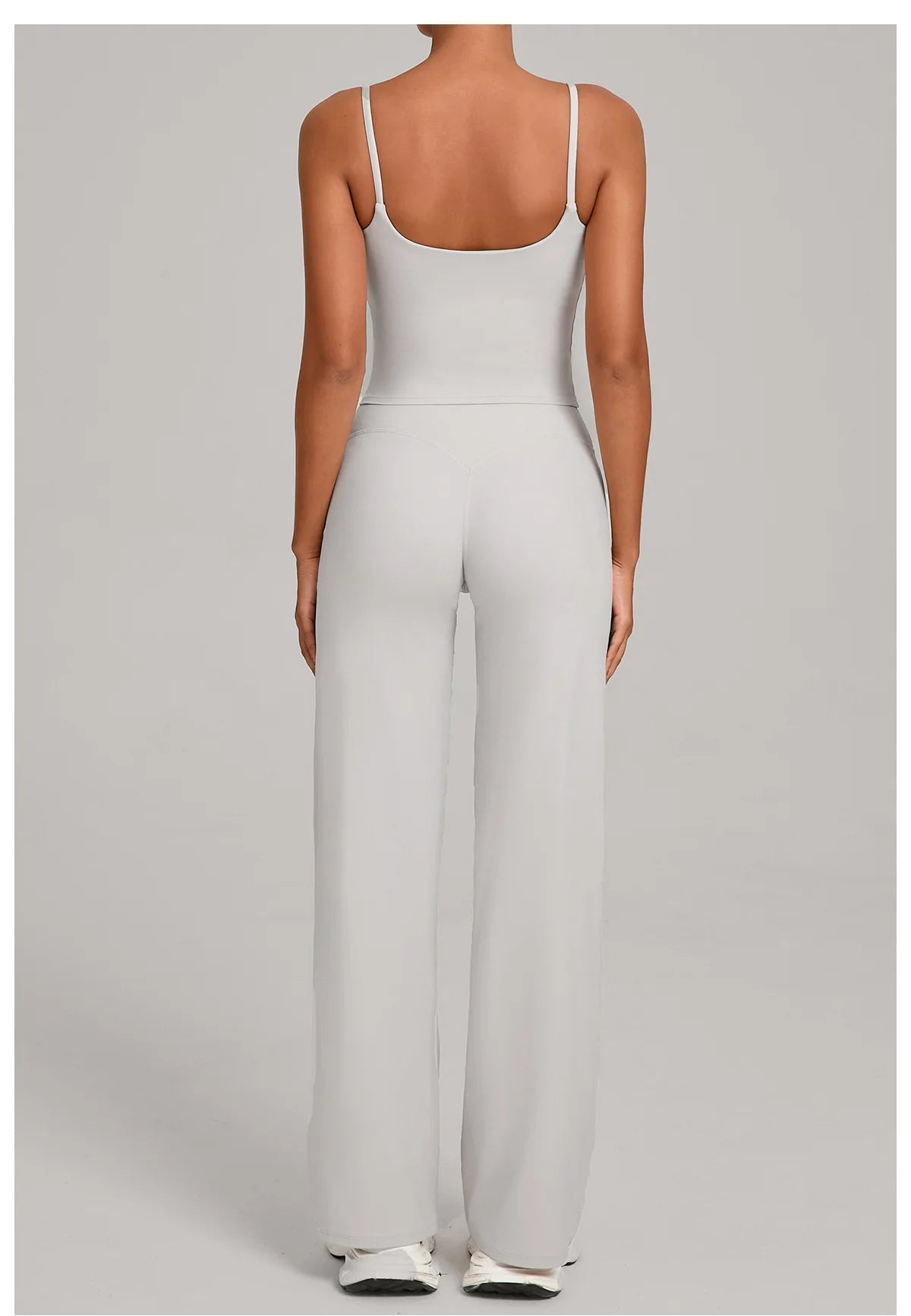 A woman models a light gray high-waist yoga and fitness tracksuit set top and pants.