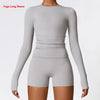A model wearing a light gray long sleeve yoga top and matching shorts.