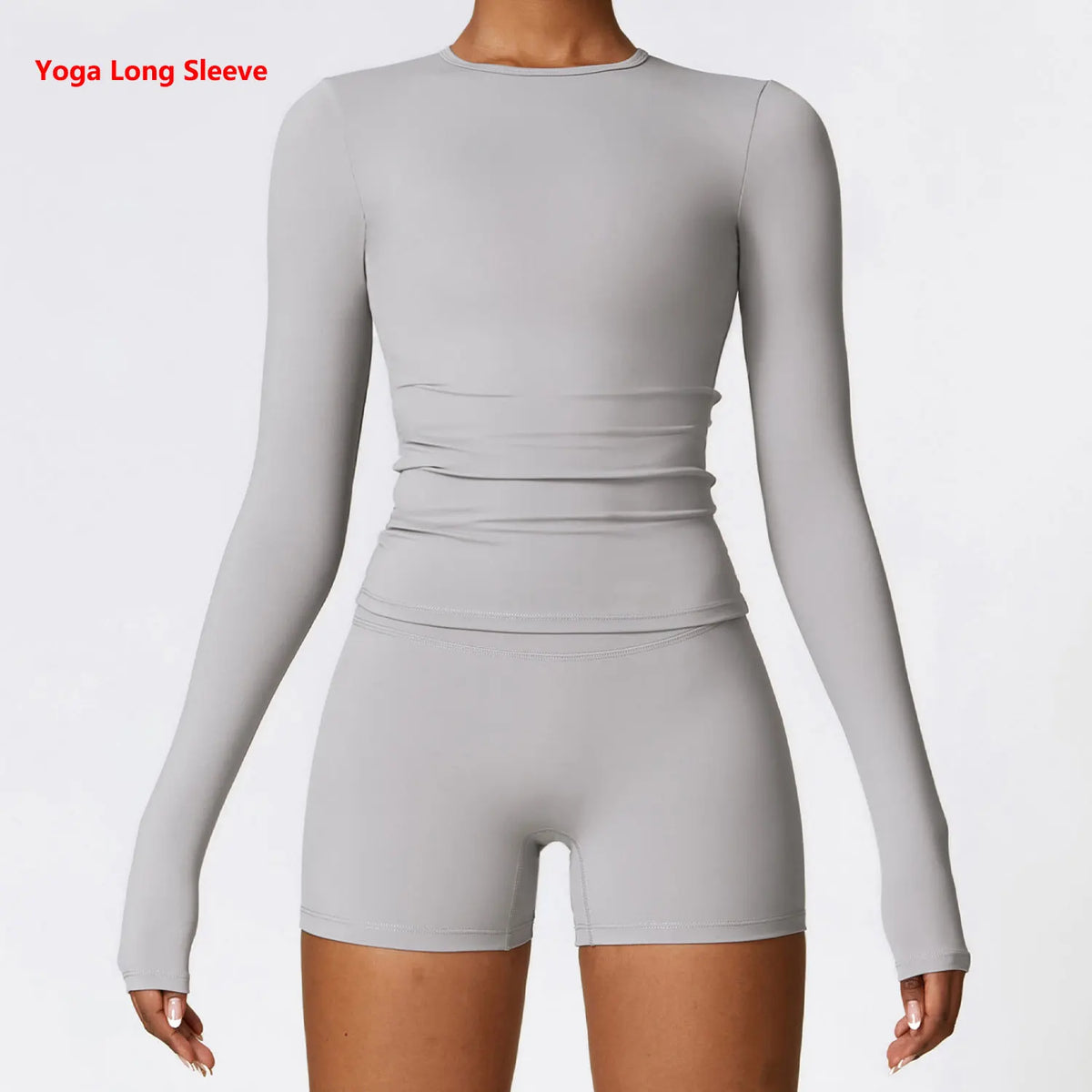 A model wearing a light gray long sleeve yoga top and matching shorts.