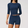 A woman wearing a navy blue long-sleeved top and matching high-waisted leggings set for yoga or fitness.