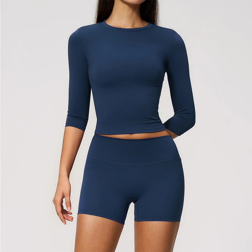 A woman wearing a navy blue long-sleeved top and matching high-waisted leggings set for yoga or fitness.